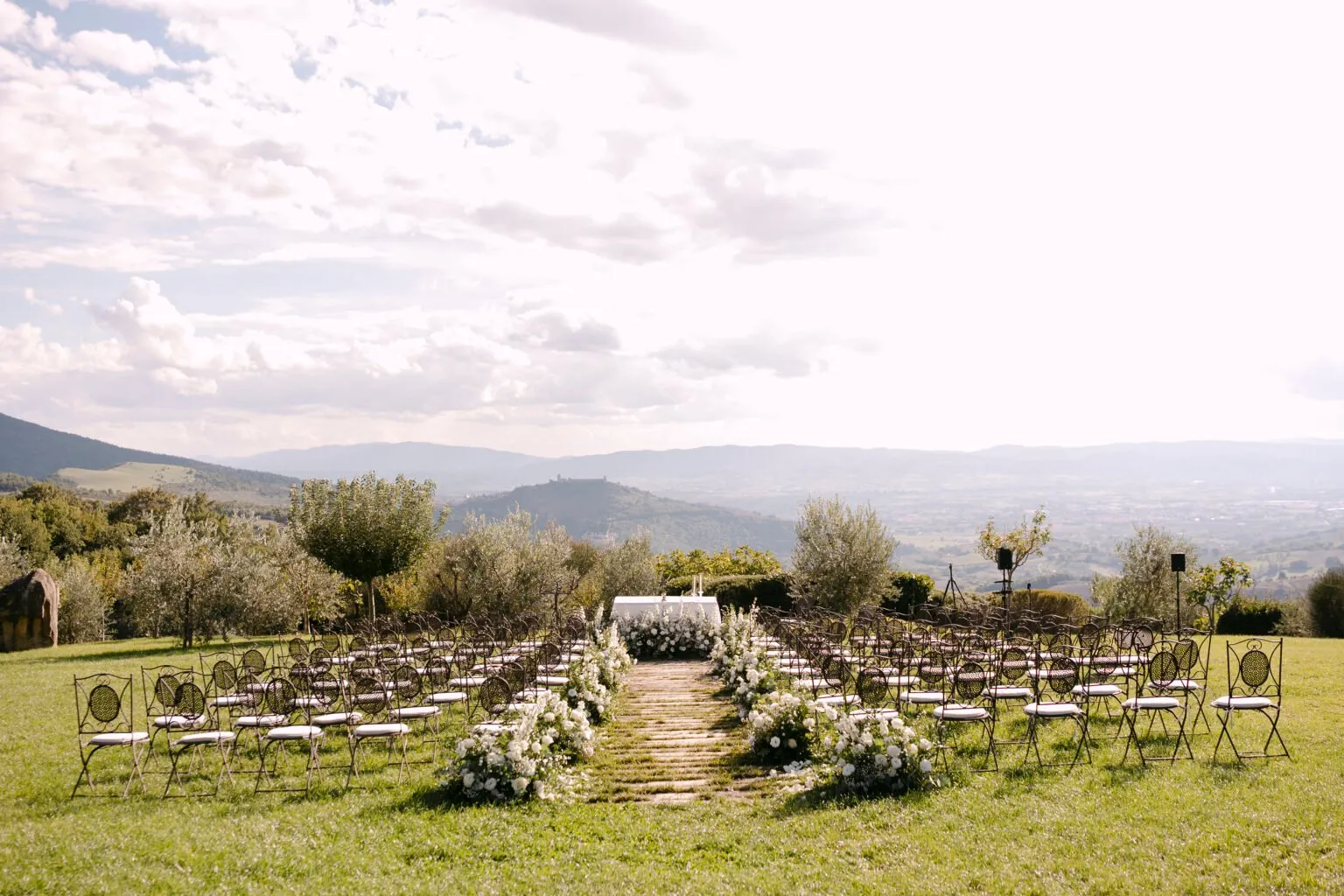 Cadeiras e flores brancas prontas para a cerimônia de Laura e João, com vista para as colinas